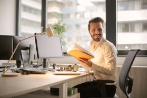 homem a trabalhar ao computador com livro