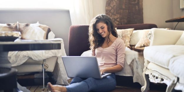mulher contente em casa a trabalhar ao computador