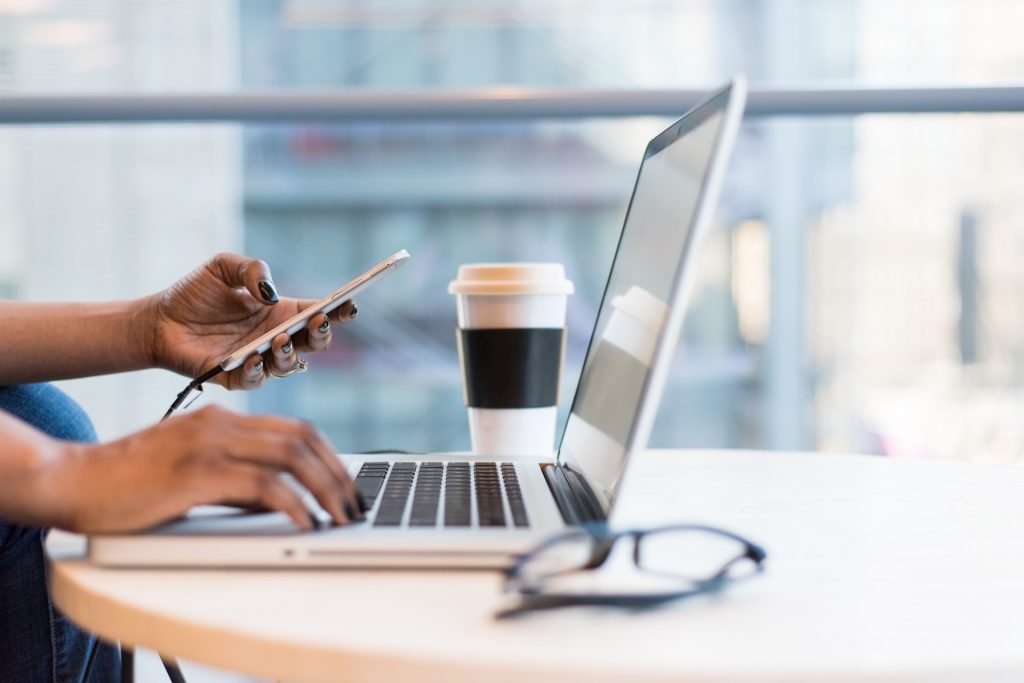 mulher a usar computador e telemovel para comunicar